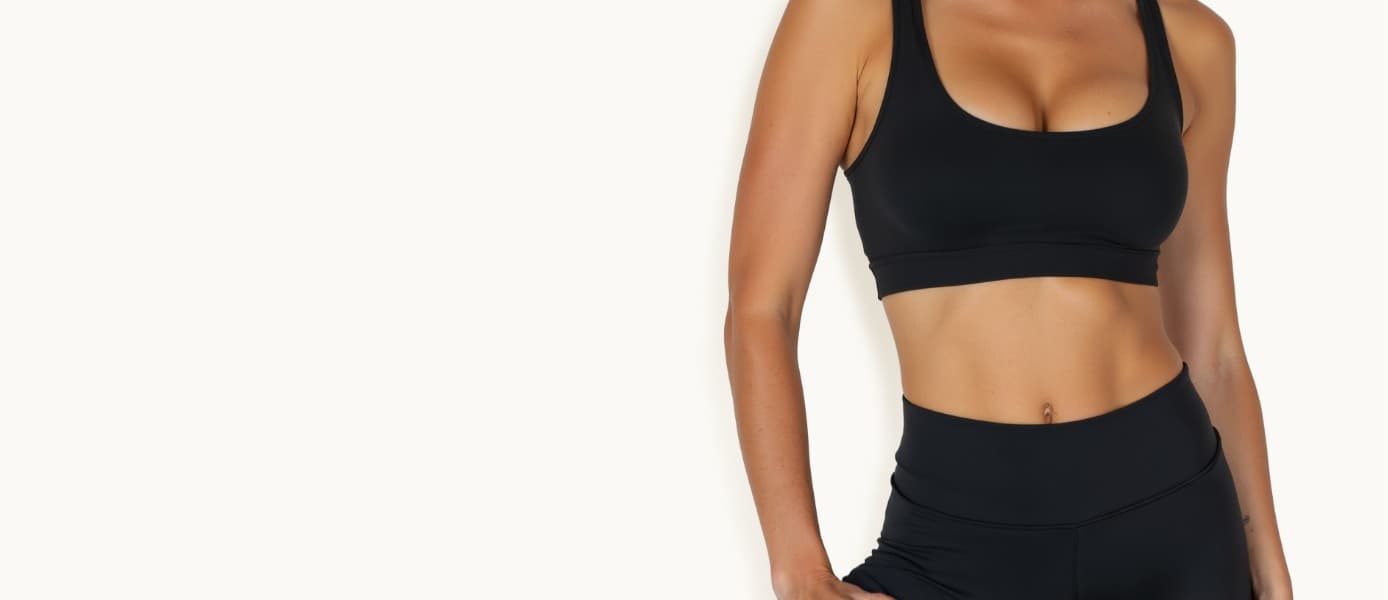 Woman in black athletic wear shown from shoulders to waist