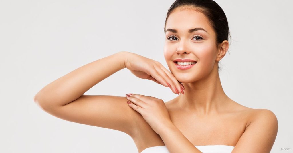 Woman with her arm lifted and resting her hand on her chin. (Model)