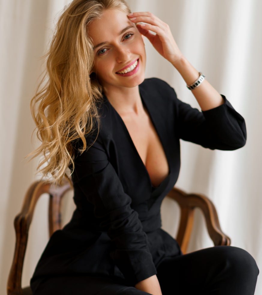 Smiling blonde model seated in a black blazer