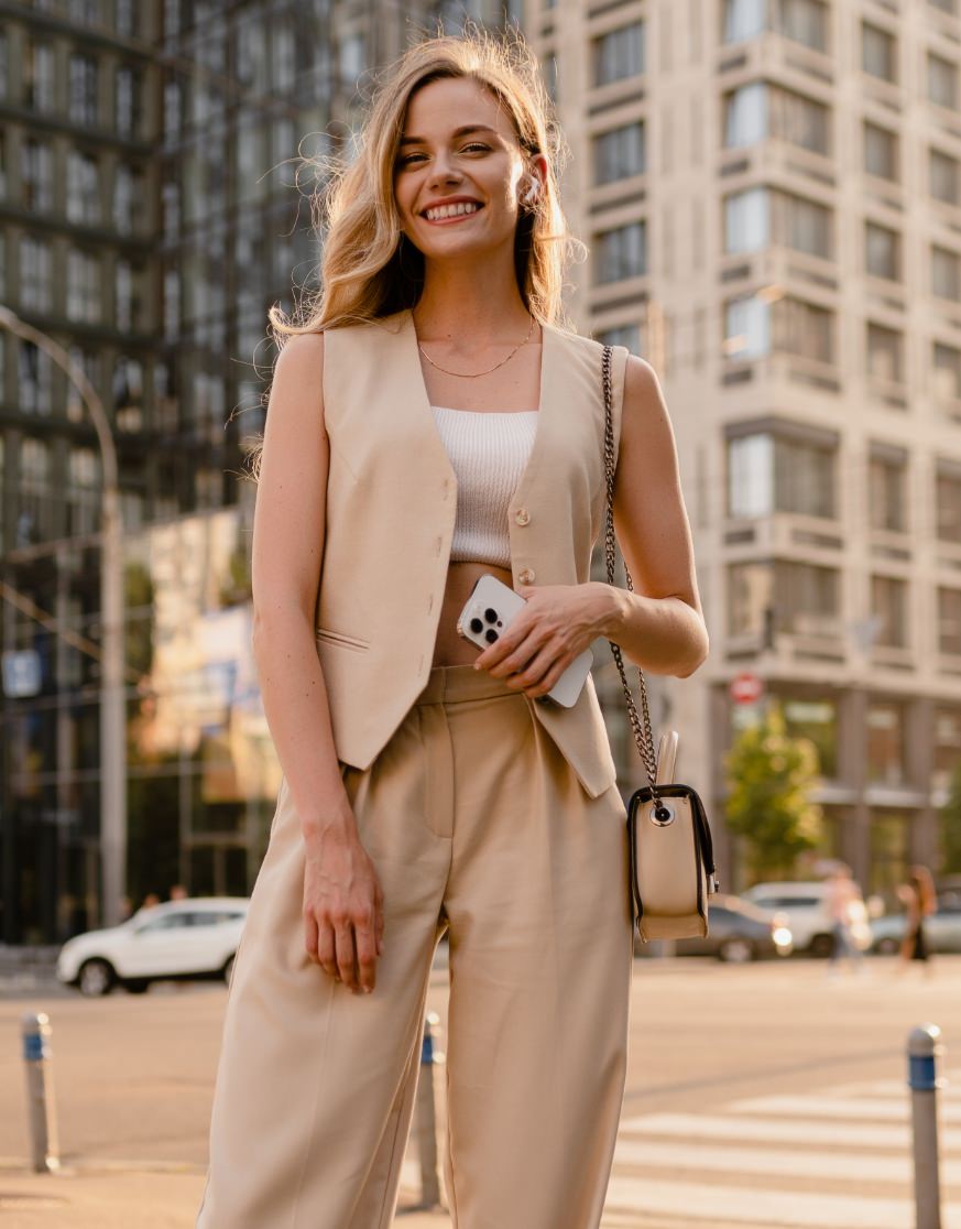 Smiling blonde model standing in a beige outfit